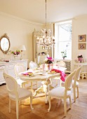 Weisses Esszimmer mit Tisch und Stühlen im Neo-Rokokostil unter Kronleuchter