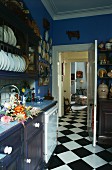 Blau getönte Landhausküche mit offener Tür und durchgehendem Schachbrettmusterboden
