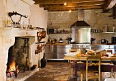 Rustikale Landhausküche mit Edelstahl-Küchenzeile, Esstisch aus Holz & offenem Kamin