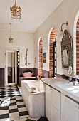 Spacious bathroom with bathtub, arched French windows and chequered floor