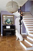 Antique, spherical, crystal pendant lamp in renovated foyer; girl climbing on metal pillar next to staircase