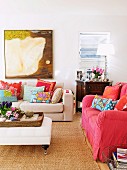 Living area with comfortable upholstered furniture and lots of colorful decorative pillows; a carpet of natural fibers on the floor