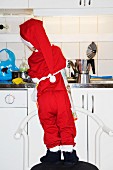Kleiner Junge, als Weihnachtsmann verkleidet, wäscht Geschirr ab