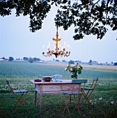 Romantic outdoor dinner with candle chandelier hanging from tree