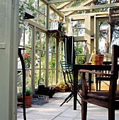 Tisch und Stühle im Gewächshaus aus Holz- und Glaskonstruktion