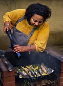 Woman cooking at barbecue grill using pepper mill
