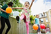 Mother and daughters playing in garden with balloons