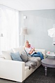 Mutter mit Baby im Arm auf modernem Sofa in Wohnzimmerecke