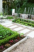 Symmetrischer Garten mit klar umrissenen Blumen- und Gemüsebeeten und einem Kieselweg mit rechteckigen Steinplatten