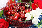 Cherries and white blossom in red glass dish