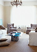 Pale grey armchairs and sofa around DIY coffee table in simple living room