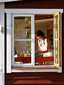 View through open window of woman in kitchen