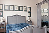 Nostalgisch eingerichtetes Schlafzimmer mit grauen Möbeln und gerahmten Bildern an der Wand