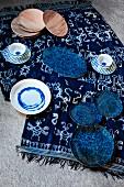 Blau-weiss gemustertes Geschirr und Holzteller auf farblich abgestimmtem Tuch