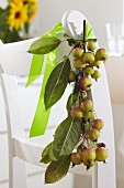 Branch of crab apples tied to back of chair with satin ribbon
