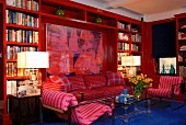 Red bookcase in modern living room with large painting and blue floor