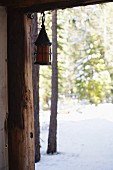 Lantern hanging from wooden beam of log cabin