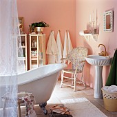 Romantically furnished bathroom with pink walls & free-standing bathtub