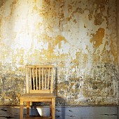 Simple wooden chair against peeling wall