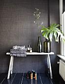 Rustikaler Wandtisch an Badezimmerwand mit anthrazitfarbenen Mosaikfliesen