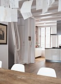 Sheets of paper hanging over dining table in open-plan interior