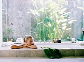 Junge Frau entspannt in einer im Boden eingelassenen Badewanne