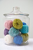 Balls of wool of various colours in glass jar