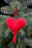 Red, hand-knitted yarn heart as Christmas tree decoration