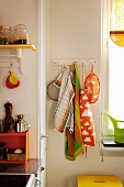 Colourful tea towels on hooks in corner of kitchen next to window