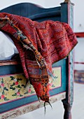 Old, embroidered, dark red, Hungarian shawl used as blanket on painted, 19th century rustic bed