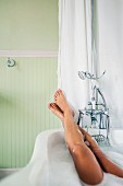 Young woman stretching legs in bathtub