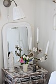 Madonna figurine, ornate shabby chic candelabra and bouquet of spring flowers in front of mirror on distressed, small, antique table