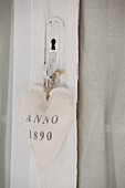 Fabric heart with printed motif tied to old, white-painted door handle with cord