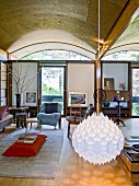 White, droplet-shaped pendant lamp in comfortable living room with eclectic furnishings and barrel-vaulted ceiling