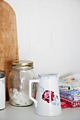 China jug with stylised rose motif, sugar cubes in storage jar and romantically patterned tea towels
