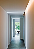 Long, narrow hallway with indirect lighting and view of the greenery