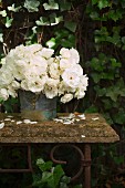 White roses in zinc bucket on vintage garden table