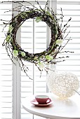 Easter wreath of willow catkins and white tulips in window and egg-shaped ornament on table