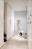 Spacious, white cloakroom with full-length mirror and black and white fabric bags