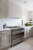 Extractor hood above electric cooker in Scandinavian cooker with pale grey fronts