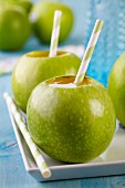 Grüne Äpfel als Trinkgefäße mit Strohhalm