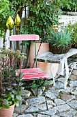 Decorative rods, old garden furniture and potted plants on stone cobbles in garden