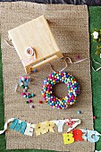 Colorful DIY wreath made of felt balls and garland with fabric letters clipped to a ribbon