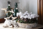 Gebastelter Kranz aus Birkenrinde mit weissen Alpenveilchen, Sterne aus Birkenzweigen und Vintage Flaschen