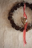 Wreath of pine cones and barbed-wire plant tied with red ribbon