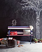 Romantic park atmosphere in living room with colourfully painted garden bench and tree and bird drawn on chalkboard wall