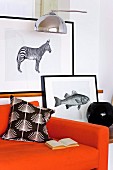 Black-framed animal graphics behind an orange sofa
