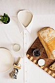 Tablecloth hand-made from men's shirt on table with wooden board, bread, spread, plate and napkin