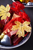Small gift bags decorated with dried, painted autumn leaves