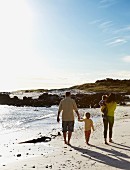 Family with two young children walking on beach